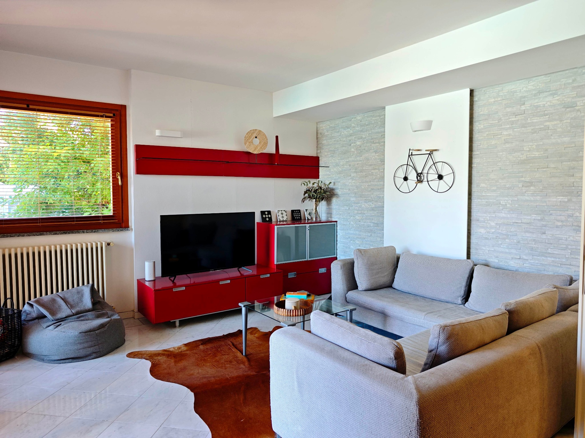 Living room with grey sofas, cowhide rug and a decorative bicycle on the stone-clad wall
