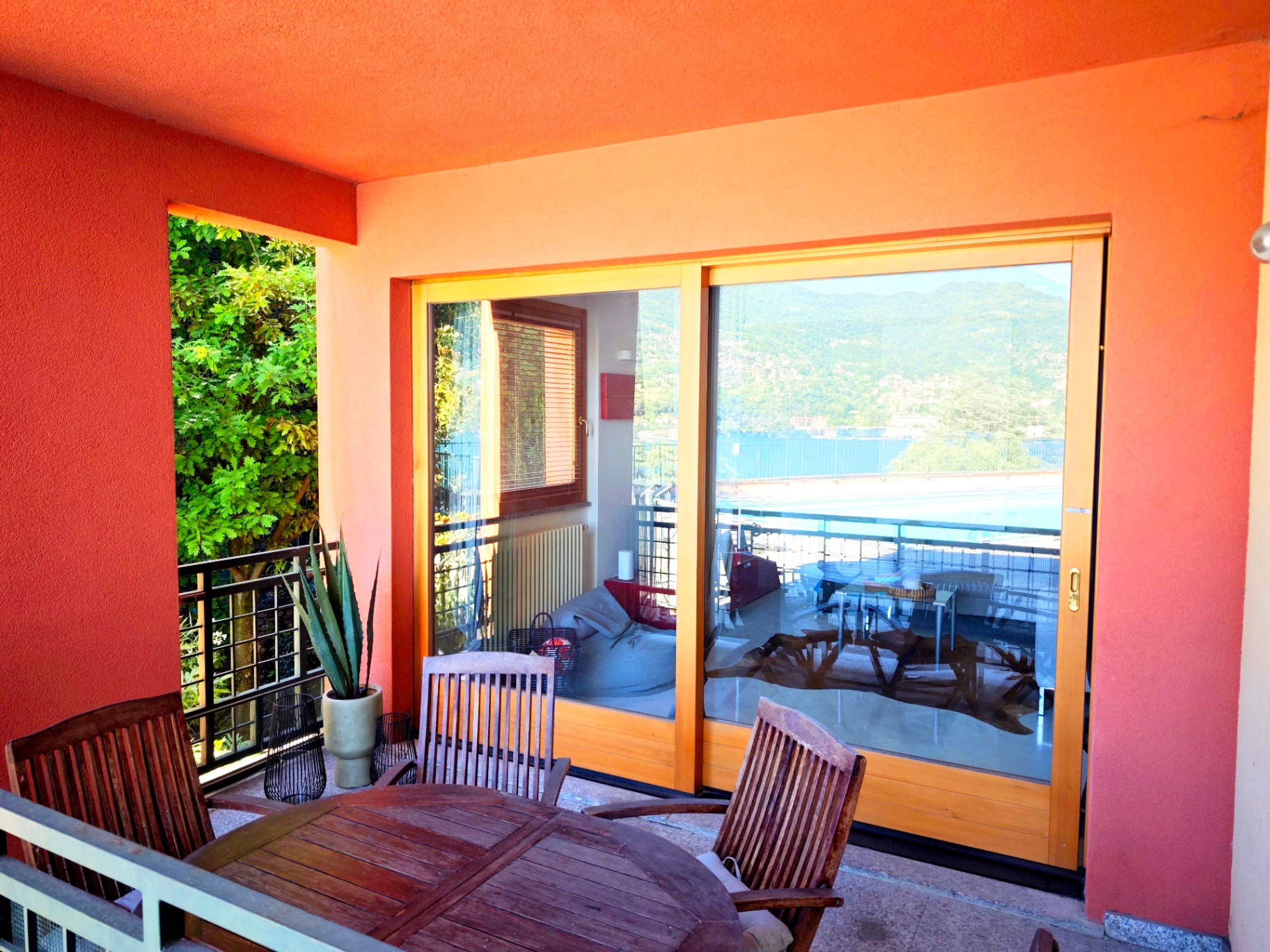 Orange-walled terrace with wooden dining set, agave plant and Lake Como view