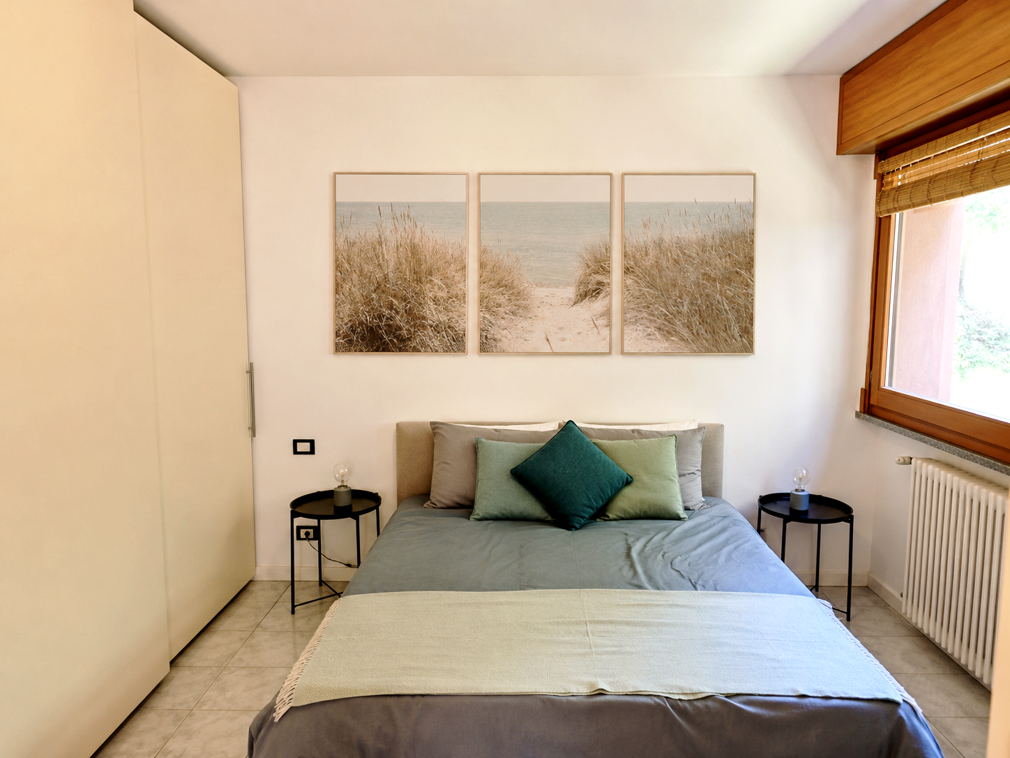 Main bedroom with double bed, framed artwork and warm natural light