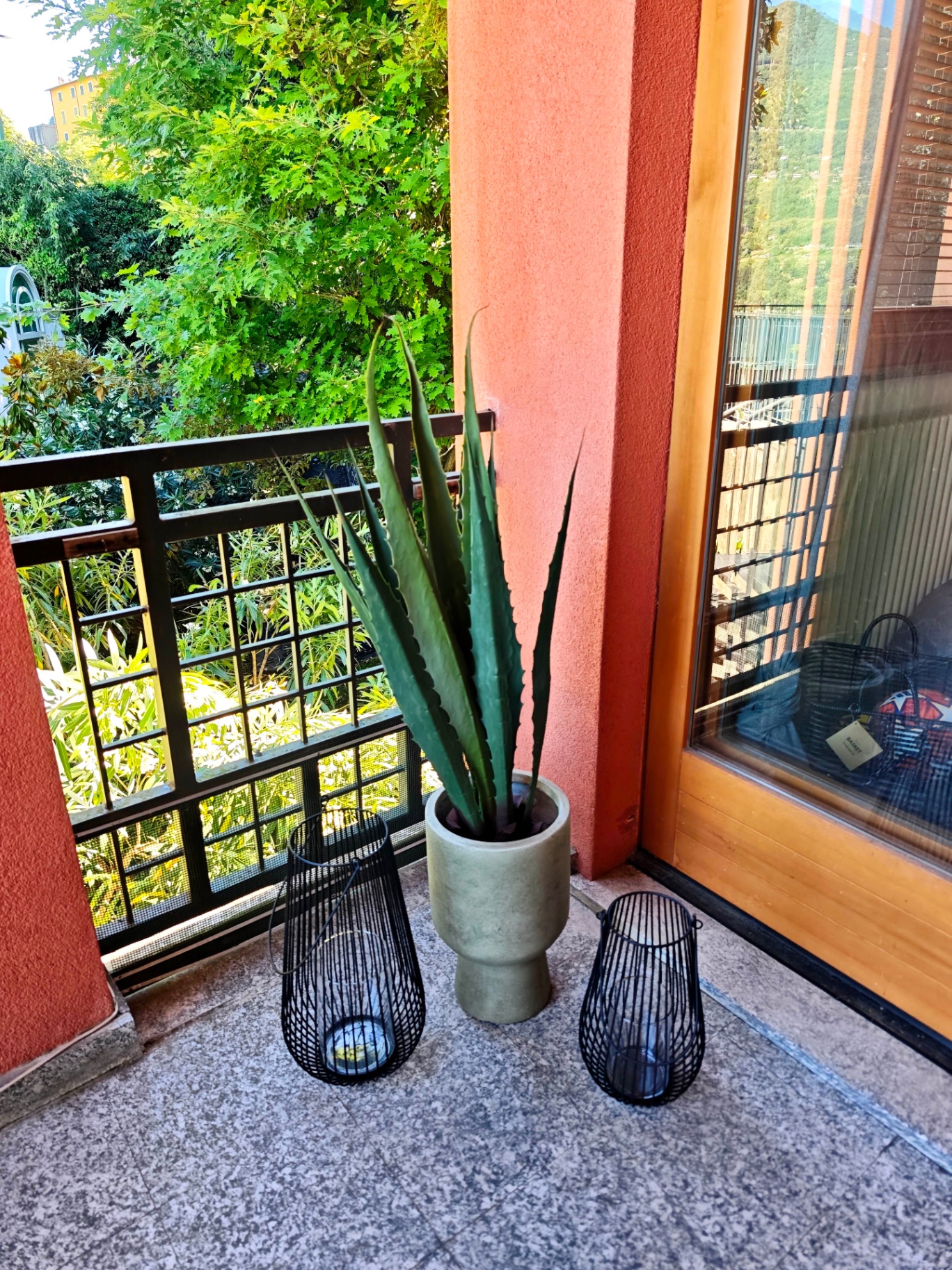 Corner of the terrace with an agave in a stone pot and black wire lanterns