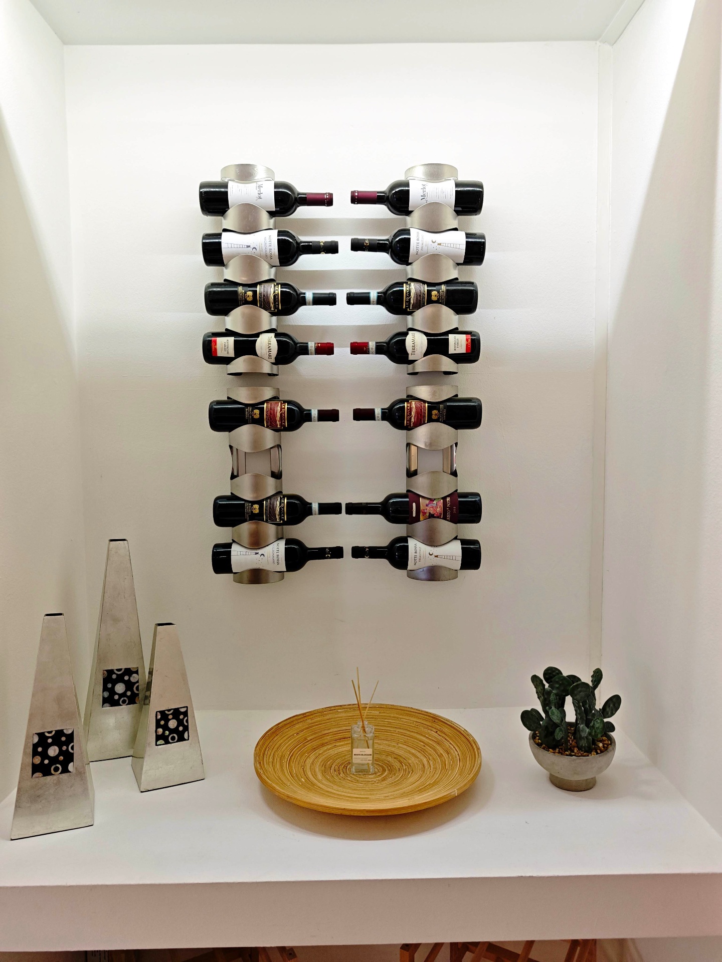 Wall-mounted wine rack stocked with Italian reds above a console with a diffuser