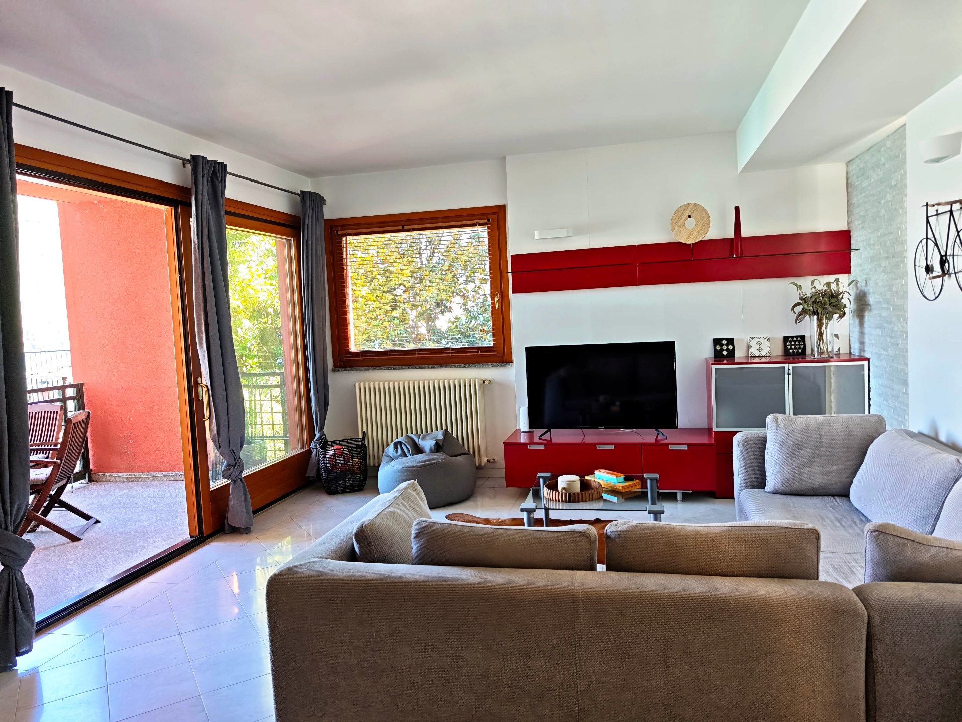 Open-plan living room with sliding doors onto the terrace and a red media wall